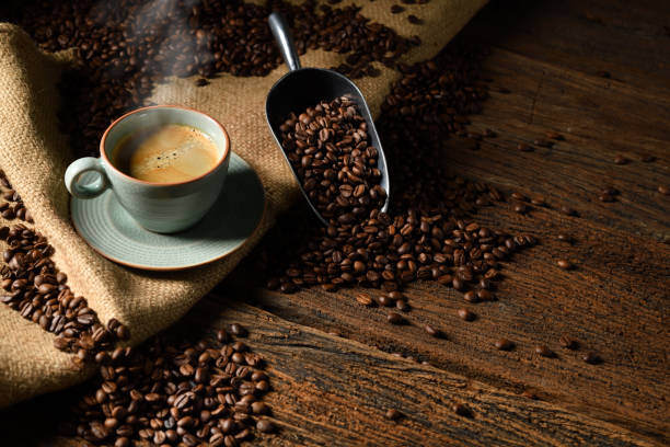 Coffee cup with coffee surrounded by a scoop filled with fresh coffee beans. dark, light, flavourful, delightful coffee. grounds beans hot coffee Coffee cup with coffee surrounded by a scoop filled with fresh coffee beans. dark, light, flavourful, delightful coffee. grounds beans hot coffee